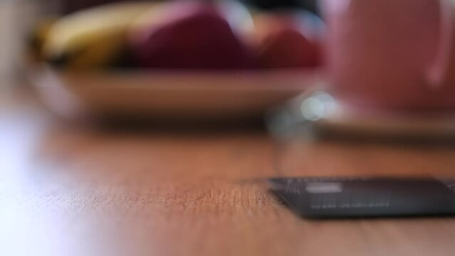 Slow motion, credit cards fall on wooden table close-up view on blurred background. Financial services, payment methods, and the economy.