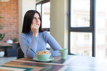 pretty young woman feeling scared, worried or angry and looking to the side. breakfast concept