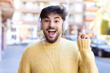 young handsome man feeling like a happy and excited genius after realizing an idea. listening music with headphones