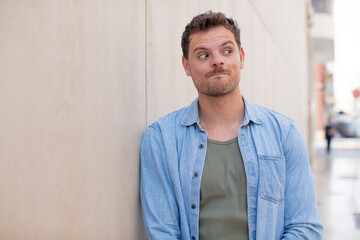 Obraz premium handsome man wondering, thinking happy thoughts and ideas, daydreaming, looking to copy space on side