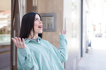 young pretty woman feeling happy, amazed, lucky and surprised, celebrating victory with both hands up in the air