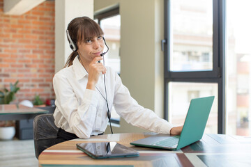 young pretty woman smiling with a happy, confident expression with hand on chin. telemarketer concept