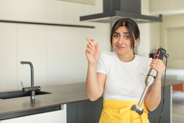 young woman crossing fingers and hoping for good luck. chef with hand blender