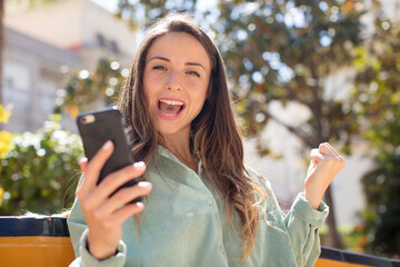 pretty woman feeling shocked,laughing and celebrating success. smartphone concept