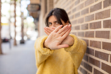 pretty woman covering face with hand and putting other hand up front to stop camera, refusing...