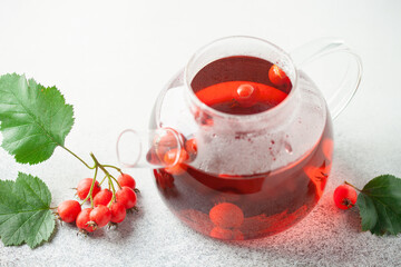 Hawthorn tea in a glass teapot and a cup on the table. Vitamin health drink.