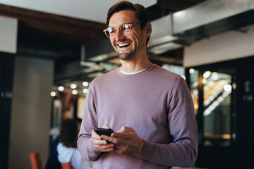 Male professional holding a mobile phone in an office