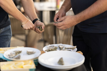 Two men open oysters with a knife