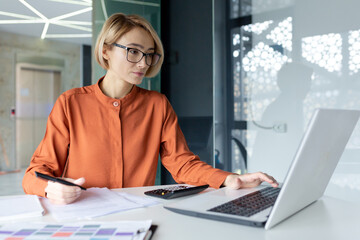 Serious successful businesswoman behind paper work inside office, financial worker thinking about...