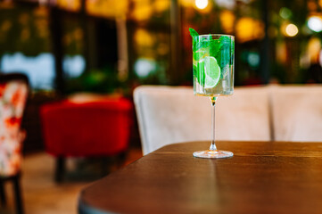 summer alcoholic cocktail mojito with ice, fresh mint and lime on table in outdoor cafe