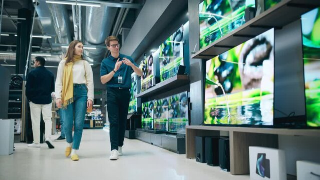 Beautiful Client Engaging in Dialogue with Retail Electronics Shop Consultant. Female Seeks Smart, Internet-Connected TV. Customer Exploring Advanced Television Choices in Modern Retail Store