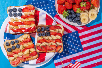 Obraz premium July 4 breakfast sandwiches, holiday snack or brunch with peanut butter, chocolate and cheese spread, with strawberries, blueberries and banana in the shape of america patriotic flag
