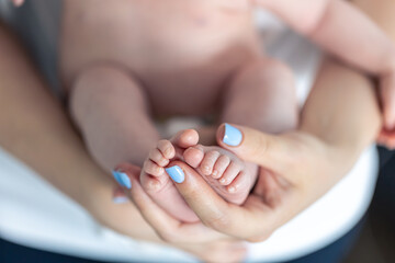 Close-up, the feet of a newborn in the hands of the mother.