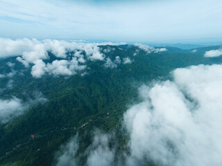 Aerial view of flowing fog waves on mountain tropical rainforest,Bird eye view image over the clouds Amazing nature background with clouds and mountain peaks in Thailand