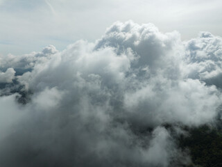 Aerial view of flowing fog waves on mountain tropical rainforest,Bird eye view image over the clouds Amazing nature background with clouds and mountain peaks in Thailand