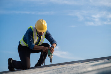 Worker repairing the roof on a construction site. Electric drill used on roof, Roof construction concept. - 612382792