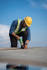Worker repairing the roof on a construction site. Electric drill used on roof, Roof construction concept. - 612382795