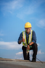 Worker repairing the roof on a construction site. Electric drill used on roof, Roof construction concept. - 612382796