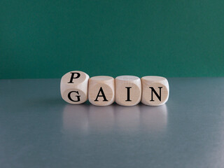 No pain no gain symbol. Turned a wooden cube and changes the word Pain to Gain. Mindset for career growth business. Beautiful grey table, green background. Business and pain gain concept. Copy space.