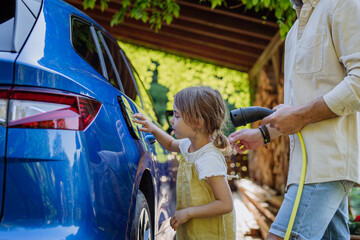 Father with his little daughter charging their electric car.
