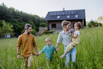Happy family in front of their house with solar panels on the roof.