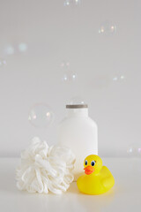 Bath concept - Sponge, douch gel and yellow duck on white table with copyspace