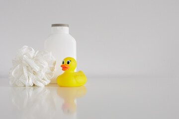 Bath concept - Sponge, douch gel and yellow duck on white table