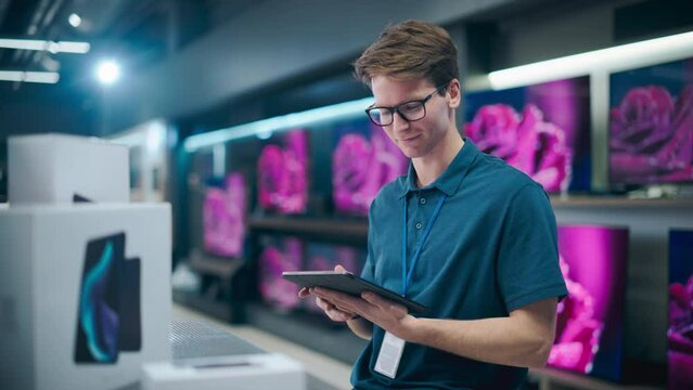 Portrait of an Organized Handsome Assistant in Home Electronics Store Optimizing Workflows with Tablet Computer. Young Happy Team Member Looking at Camera and Smiling