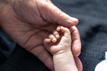 Hands of senior person and little baby close up.
