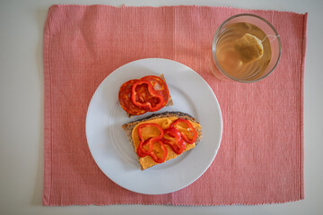 A open-facex sandwich with hummus and red pepper, and another with salami and pepper with a cup of tea.