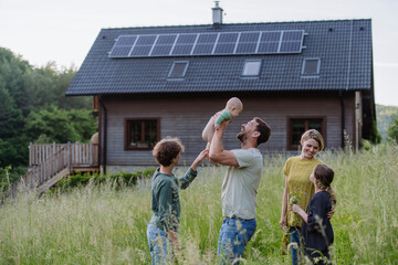 Happy family near their house with solar panels. Alternative energy, saving resources and...