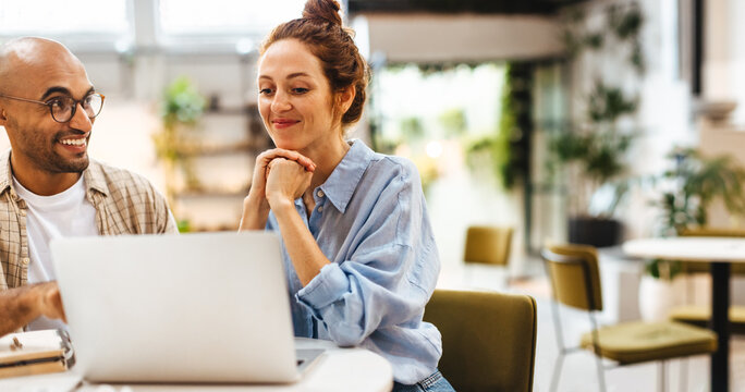 Two work colleagues using a laptop together in a coworking space