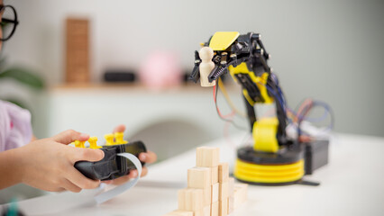 Fototapeta premium STEM education concept. Asian students learn at home by coding robot arms in STEM, mathematics engineering science technology computer code in robotics for kids' concepts