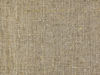 Fototapeta na wymiar Rough homespun cloth top view. A background of a scratchy burlack material in an even light brown color. Fabric made from hemp Background texture of woven canvas. Coarse-grained linen close up.