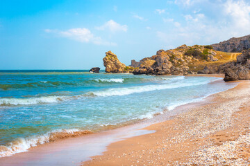 Fototapeta na wymiar Seascape. Blue sea and rocky shore with yellow sandy beach. Sea of Azov in Crimea