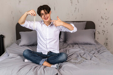 Young man on a bed with contraceptives