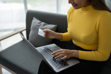 Naklejka premium Business woman, young woman holding credit card and using laptop computer for online shopping, e-commerce, banking, internet application, spending money, working from home startup business ideas