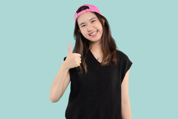 Portrait Asian beautiful teen girl smiling wear with braces shows thumb up isolated on green background, Dental hygiene and health concept.