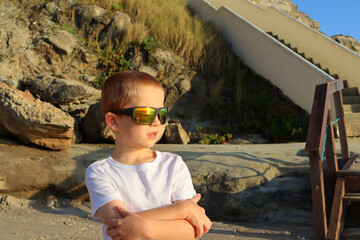 A blond boy in sunglasses looks at the Atlantic Ocean.