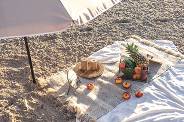 Plaid with fruits on the sandy seashore, picnic by the sea.