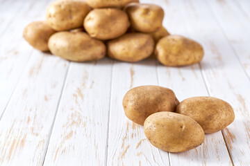Raw yellow potatoes on a white wooden table, selective focus.