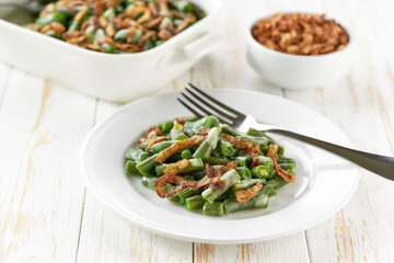 delicious green bean casserole sprinkled with crispy fried onions on a white wooden table.