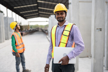 India engineer man holding laptop computer with team engineer at precast site work