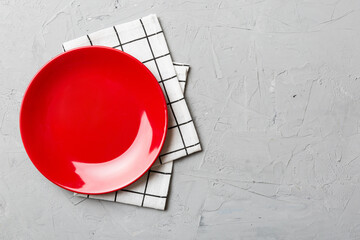 Top view on colored background empty round red plate on tablecloth for food. Empty dish on napkin...