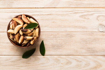 Fresh healthy Brazil nuts in bowl on colored table background. Top view Healthy eating bertholletia concept. Super foods