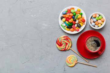 Coffee cup with chocolates and colored candy. Top view on table background with copy space