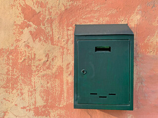 Green mailbox on the wall of an old house in the city
