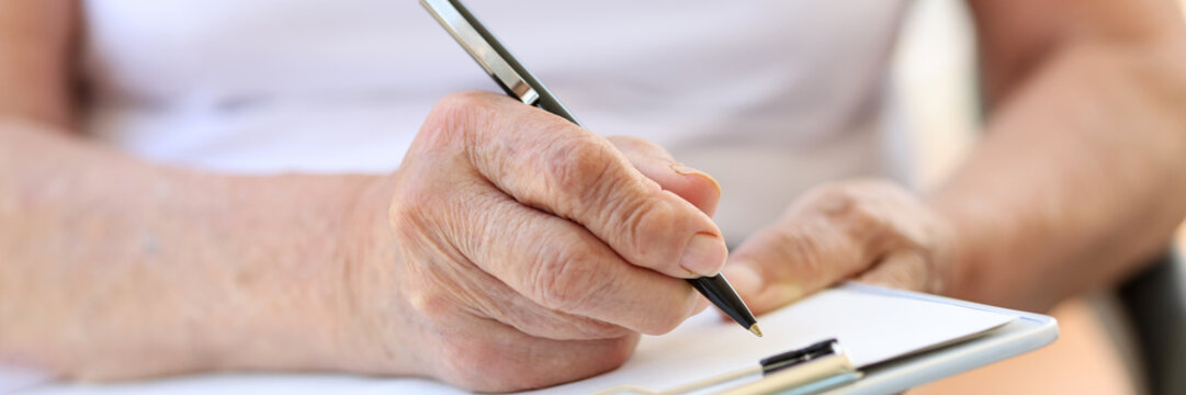 Old woman hands filling form in clinic or in hospice