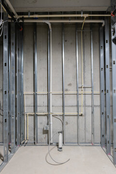 Room under construction on a commercial construction project with metal studs, PVC plumbing, and concrete walls and floors. Nobody in the image with a vertical orientation.