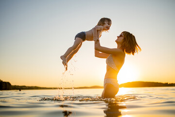 Cute toddler boy and his teenage sister playing by a lake on hot summer day. Adorable child having...